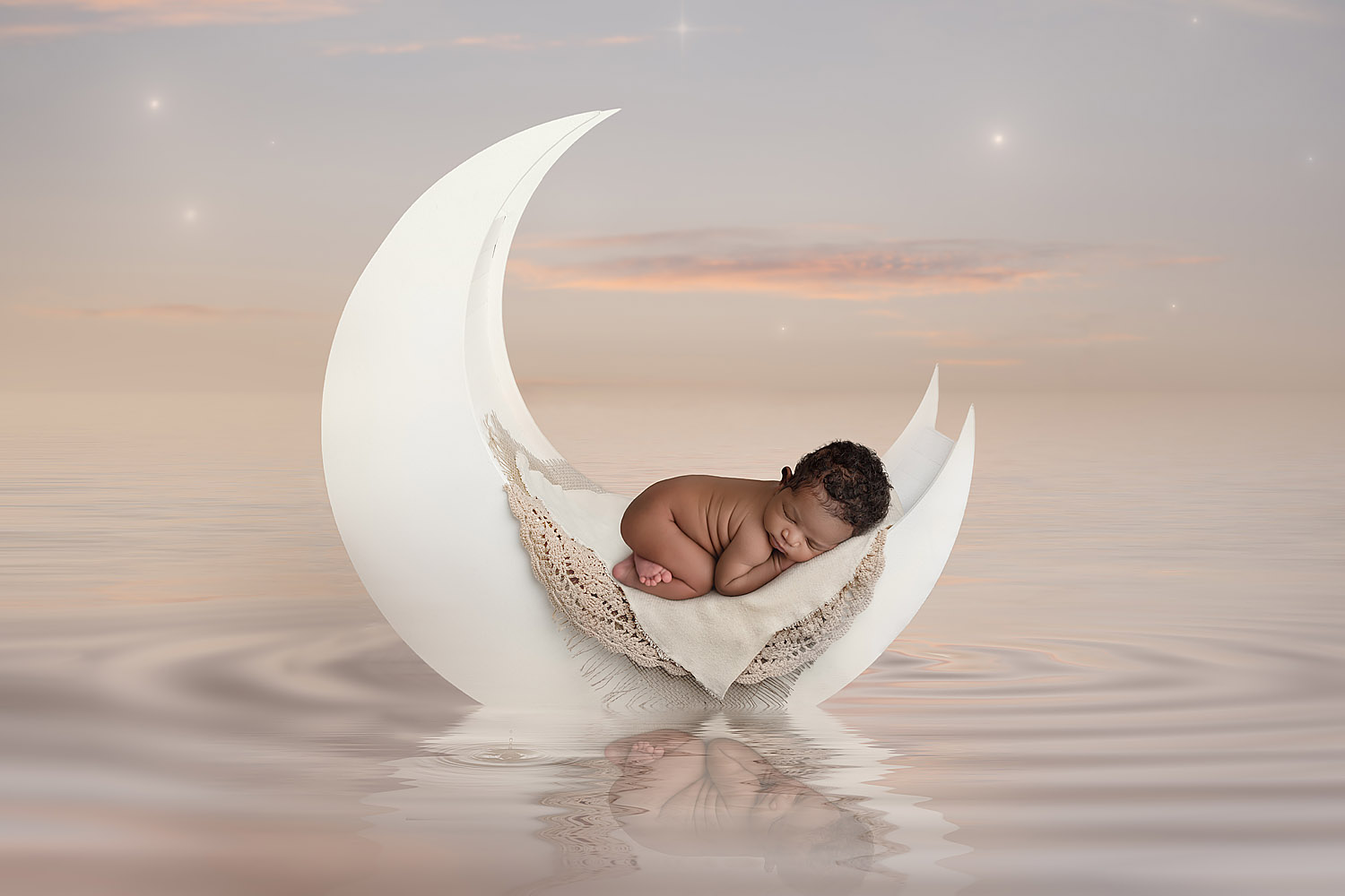 newborn baby posed on a moon prop floating on the water