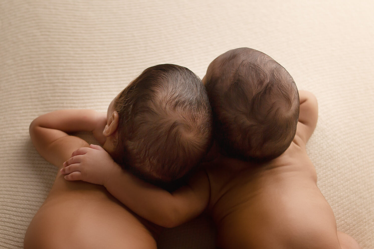 twin newborns with arm around each other