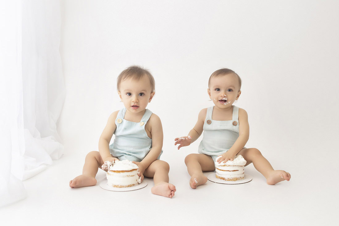 twin boys posed with cake at their first birthday cake smash session in davie fl