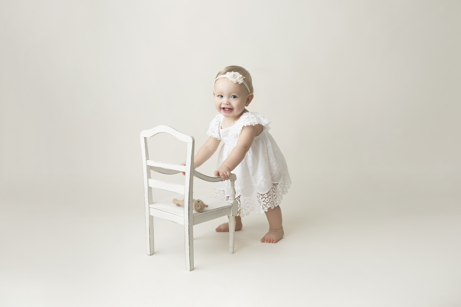 one year old standing holding onto a chair for her first birthday photoshoot in pembroke pines, fl