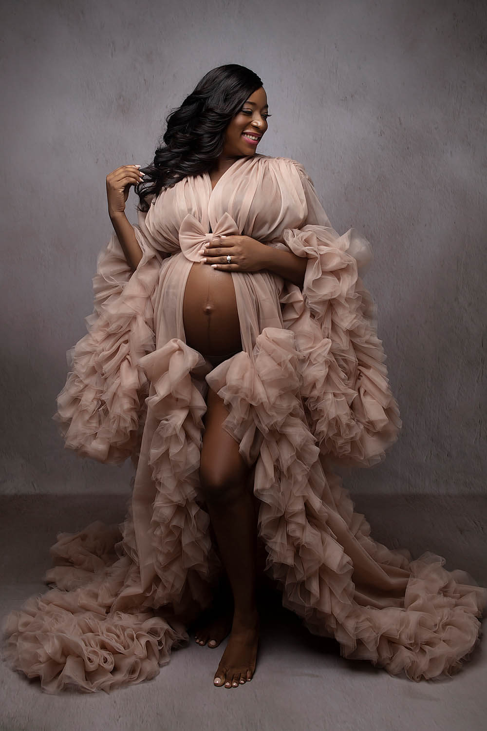 black woman wearing robe for maternity photoshoot showing her belly at a newborn photography studio in south florida near davie fl
