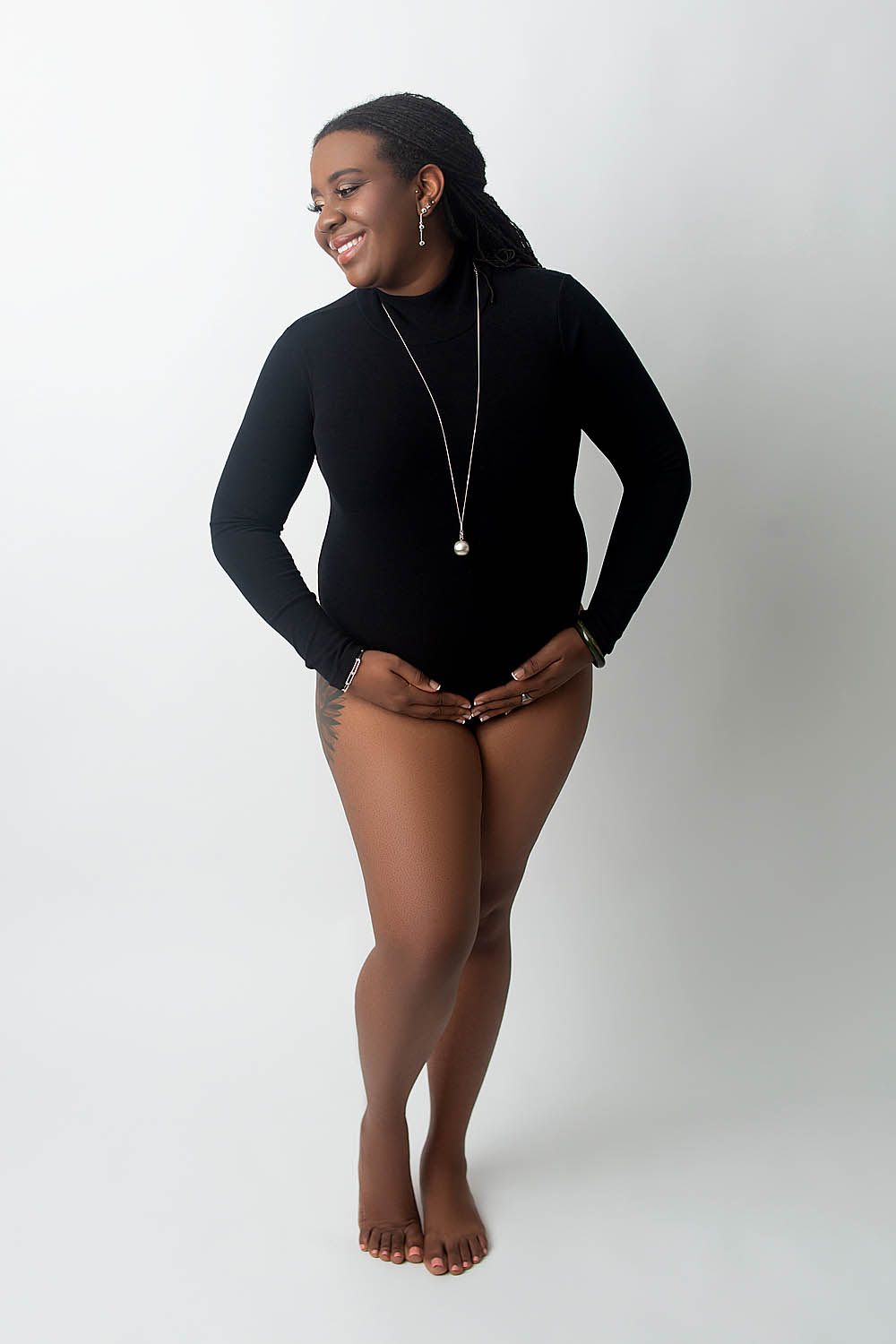 black women wearing a black bodysuit is smiling and posed at a davie photography studio that also does newborn photography near cooper city
