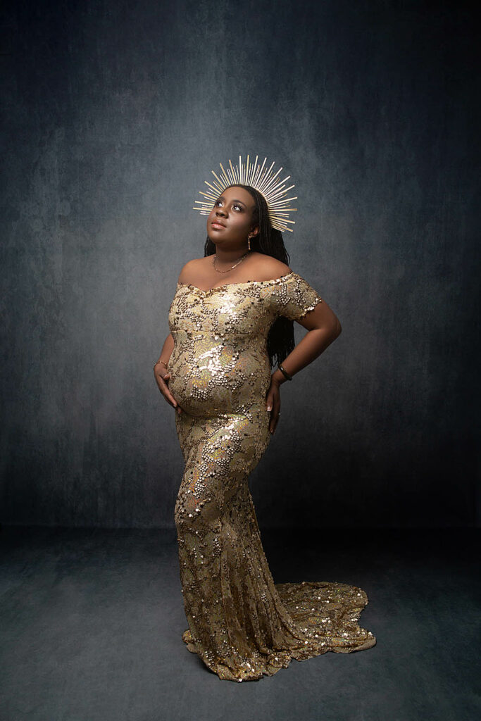 black women wearing a sparkly gold dress with a crown is posed at a cooper city photographer's studio that also does newborn photography