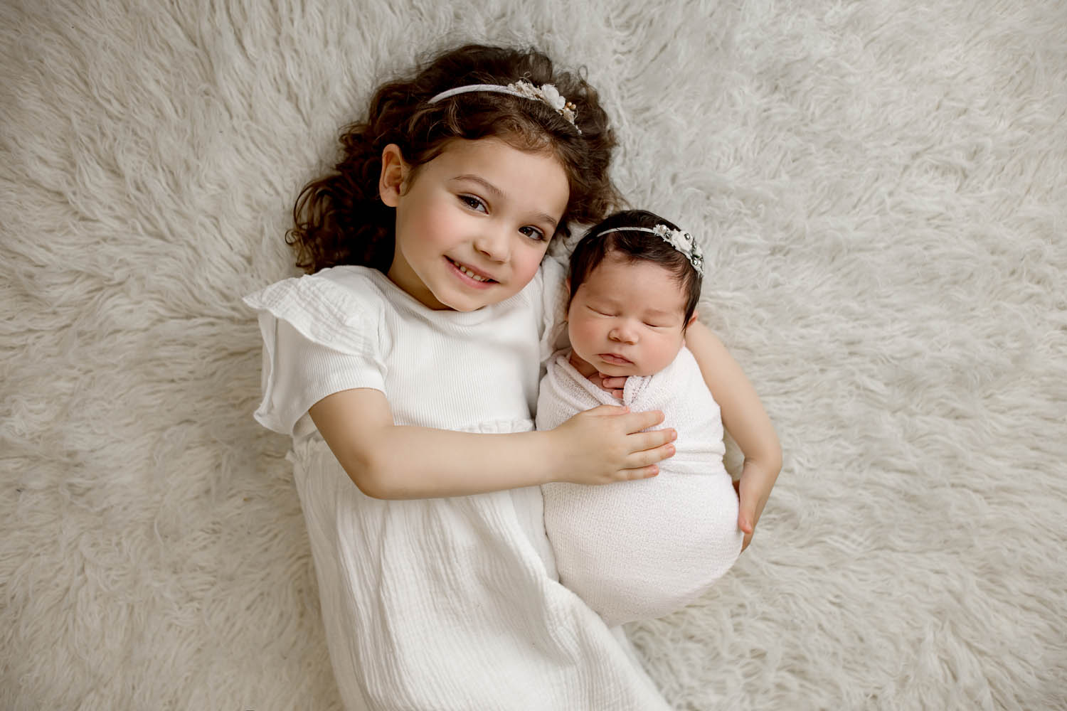 young girl posed with her newborn sister laying down at a newborn photography studio in pembroke pines near davie fl