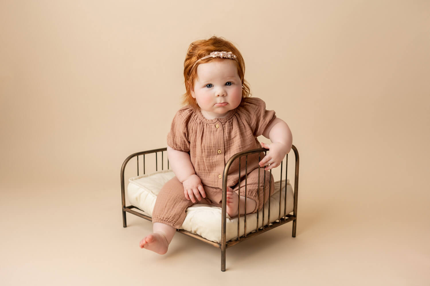 baby sitting on bed for 6 month photoshoot